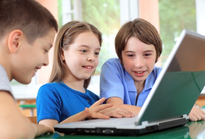 Schoolchildren having fun on laptops at classroom.