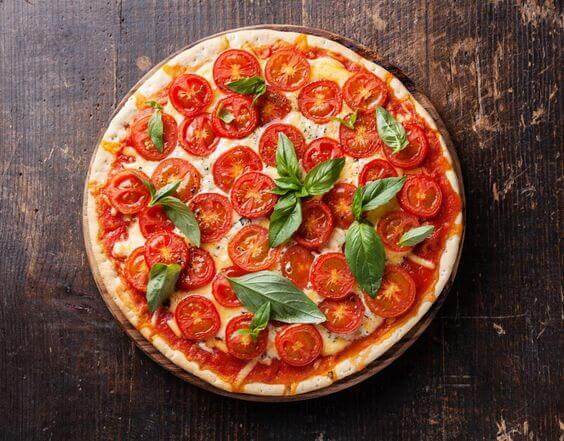 Italian pizza with cherry tomatoes and green basil on wooden table