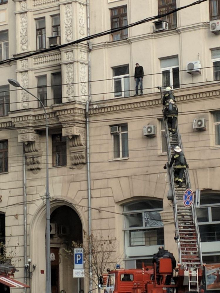 На площади Конституции мужчина выбрался на карниз дома в котором горит квартира (видео)